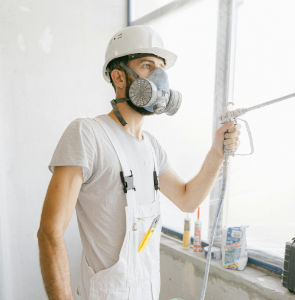 Peintre professionnel dans un apparemment en chantier portant un masque et un uniforme blanc