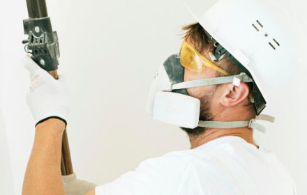 Peintre en action avec casque blanc, masque et lunette de protection