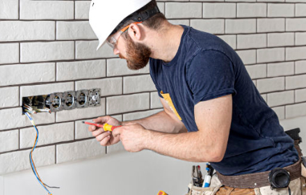 Electricien en action raccordant des câbles sur un mur possédants 4 prises électriques